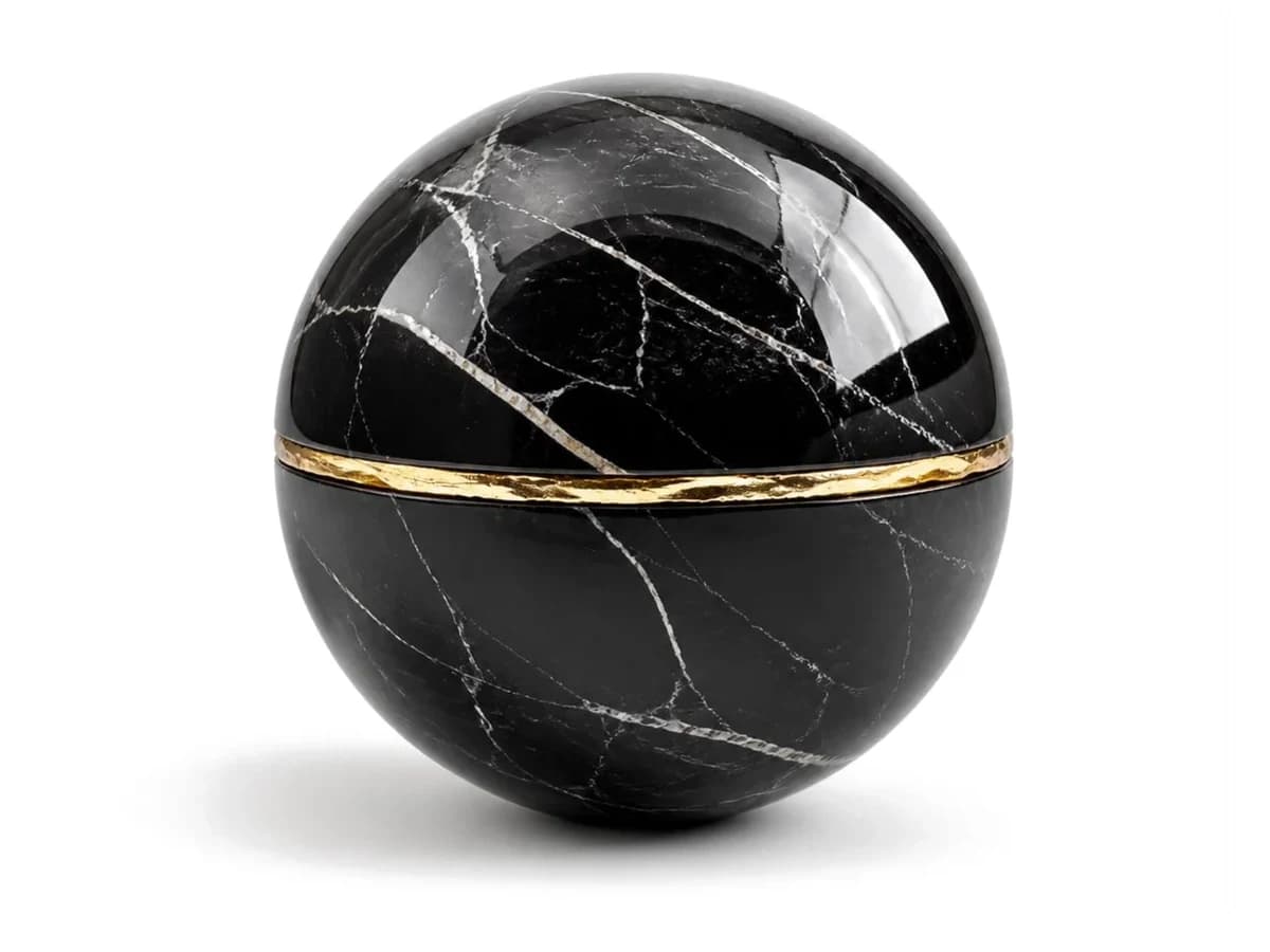 Esfera de mármol negro partida en dos y sellada con una banda de oro
